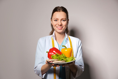 Nutritionist with healthy products on light grey background