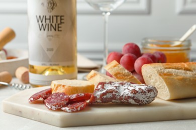 Delicious sausage, bread and bottle of white wine on table, closeup