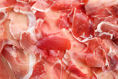 Tasty prosciutto slices as background, top view