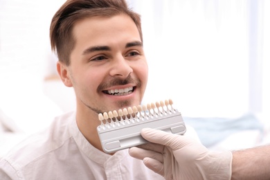 Photo of Dentist checking young man's teeth color in dental office