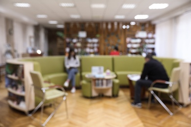 Blurred view of library interior with round sofa set and bookcases
