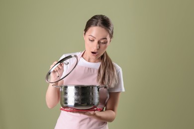 Surprised woman with pot on olive background