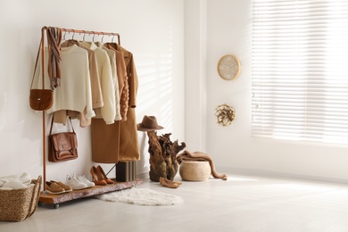 Photo of Modern dressing room interior with rack of stylish shoes and women's clothes