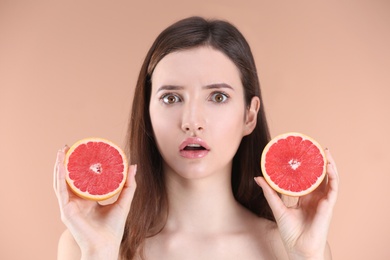 Teenage girl with acne problem holding grapefruit against color background