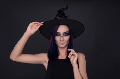 Mysterious witch wearing hat on black background