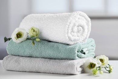 Stack of folded colorful towels with flowers on white table indoors, closeup
