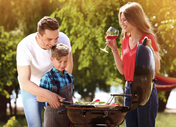 Happy family having barbecue with modern grill outdoors 