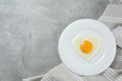 Photo of Romantic breakfast with heart shaped fried egg on light grey table, top view. Space for text