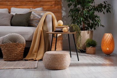 Stylish living room interior with comfortable sofa and wicker pouf