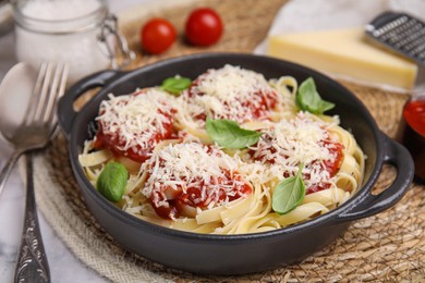 Delicious pasta with tomato sauce, basil and parmesan cheese on white marble table, closeup