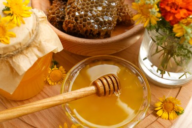 Delicious honey, combs and different flowers on wooden board