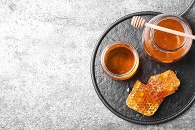 Photo of Tasty honey on grey table, top view. Space for text