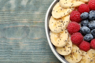 Tasty breakfast dish with berries, banana and chia seeds on wooden table, top view. Space for text