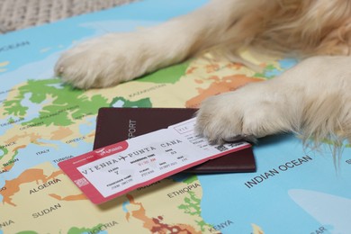 Dog lying near passport and ticket on world map, closeup. Travelling with pet