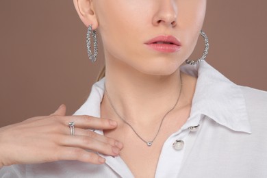Photo of Woman with elegant jewelry on light brown background, closeup