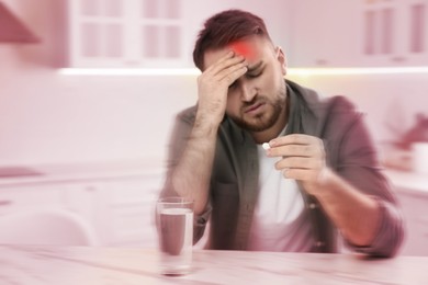 Man with pill suffering from migraine in kitchen
