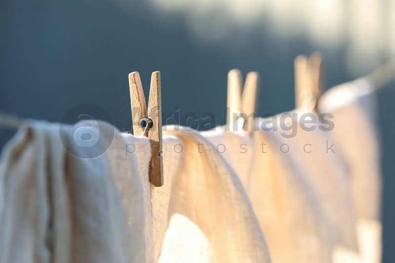 Photo of Washing line with drying shirt against blurred background, focus on clothespin