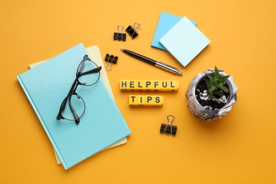 Photo of Flat lay composition with phrase Helpful Tips made of yellow cubes on orange background