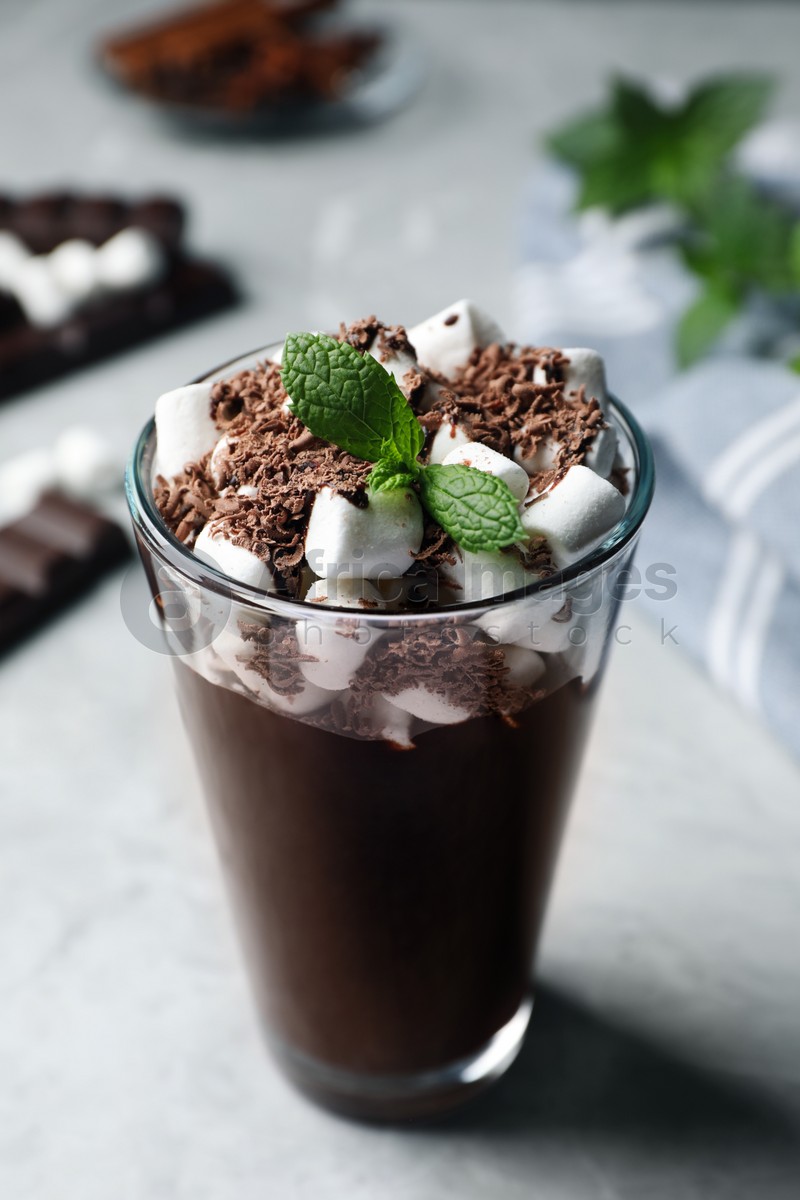 Glass of delicious hot chocolate with marshmallows and fresh mint on light grey table