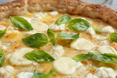 Delicious hot cheese pizza with basil on table, closeup