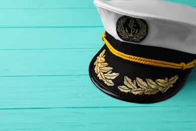 Peaked cap with accessories on turquoise wooden background, space for text