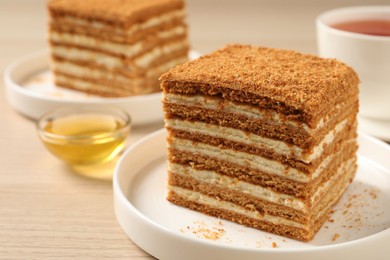 Photo of Delicious layered honey cake served on wooden table, closeup