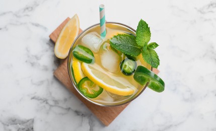 Photo of Spicy cocktail with jalapeno, lemon and mint on white marble table, top view