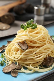 Delicious pasta with truffle slices and microgreens on plate, closeup