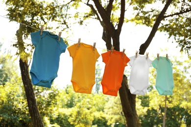 Colorful baby onesies hanging on clothes line outside