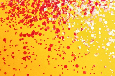 Photo of Shiny bright red glitter on yellow background
