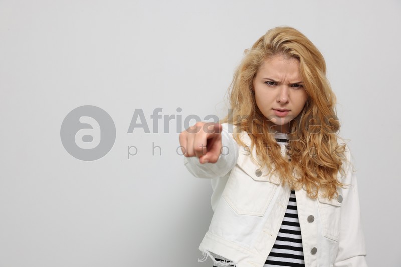 Aggressive young woman pointing on white background. Space for text