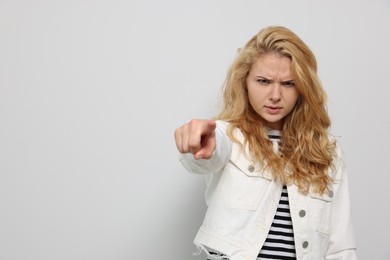 Aggressive young woman pointing on white background. Space for text