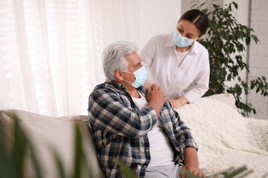 Doctor taking care of senior man with protective mask at nursing home