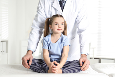 Professional orthopedist examining little girl in clinic