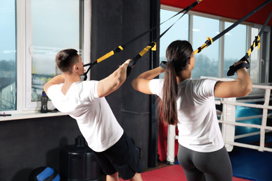 Couple working out with TRX system in gym