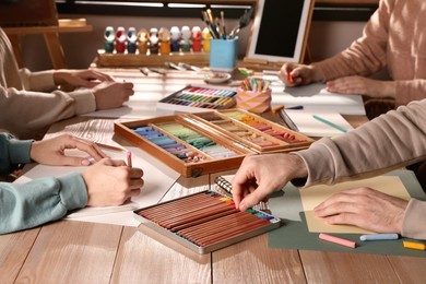 Artists drawing with soft pastels and pencils at table, closeup