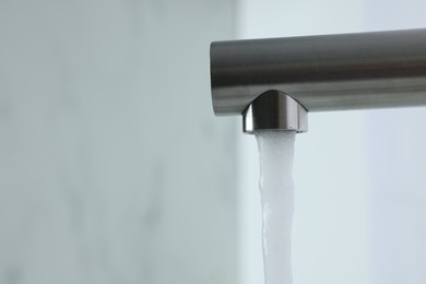 Photo of Stream of water flowing from tap on white background, closeup. Space for text