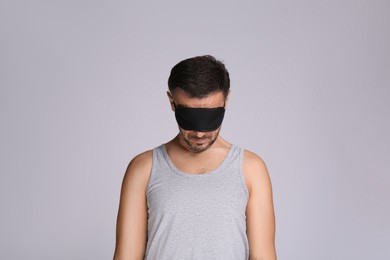 Man with eye mask in sleepwalking state on grey background