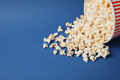 Delicious popcorn in paper bucket on blue background