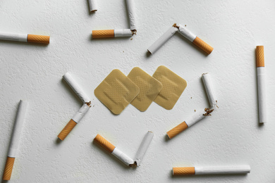 Nicotine patches and broken cigarettes on white background, flat lay