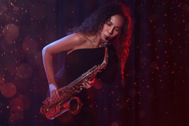 Beautiful African American woman playing saxophone on dark background. Bokeh effect