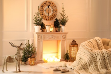 Beautiful room interior with decorative fireplace and potted fir trees. Christmas decor
