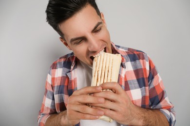 Photo of Man eating delicious shawarma on grey background
