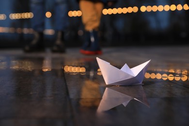White paper boat in puddle on street
