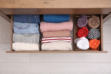 Photo of Open drawer with folded clothes indoors, top view. Vertical storage