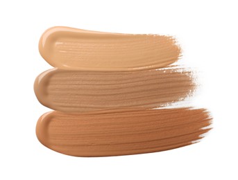 Samples of liquid skin foundation on white background, top view