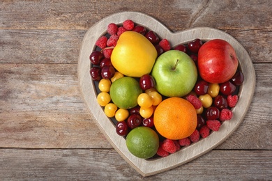 Heart shaped plate with fresh fruits on wooden table, top view. Cardiac diet