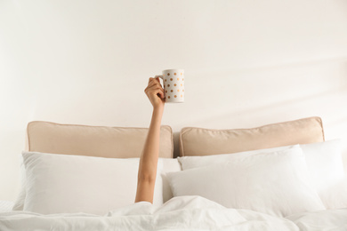 Woman with cup of coffee in bed, closeup. Lazy morning