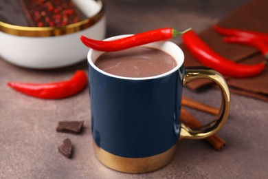 Photo of Cup of hot chocolate with chili pepper on grey table