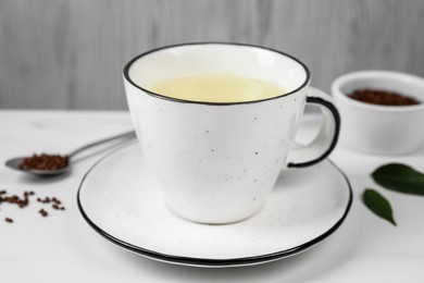 Cup of buckwheat tea on white marble table, closeup